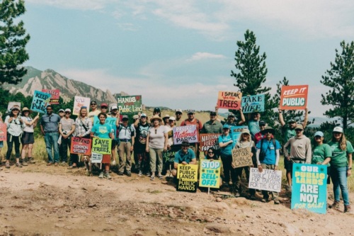 Activists gather on a mountainside at a national park holding signs.