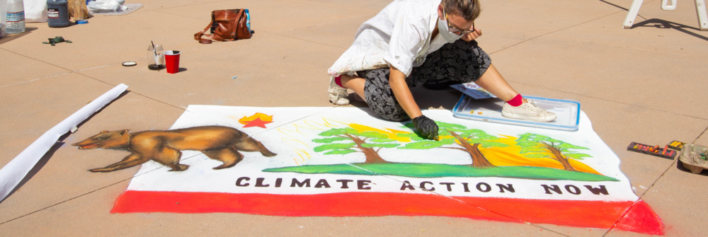 Artist paints recreation of California flag in chalk, with the words "Climate Action Now" and trees worked into the design.