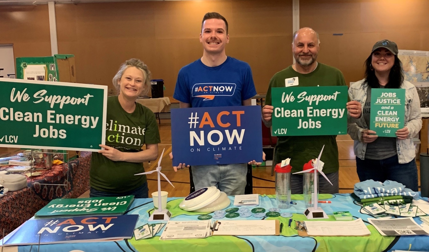 Climate Action volunteers posing at a booth with signs reading "We Support Clean Energy Jobs"