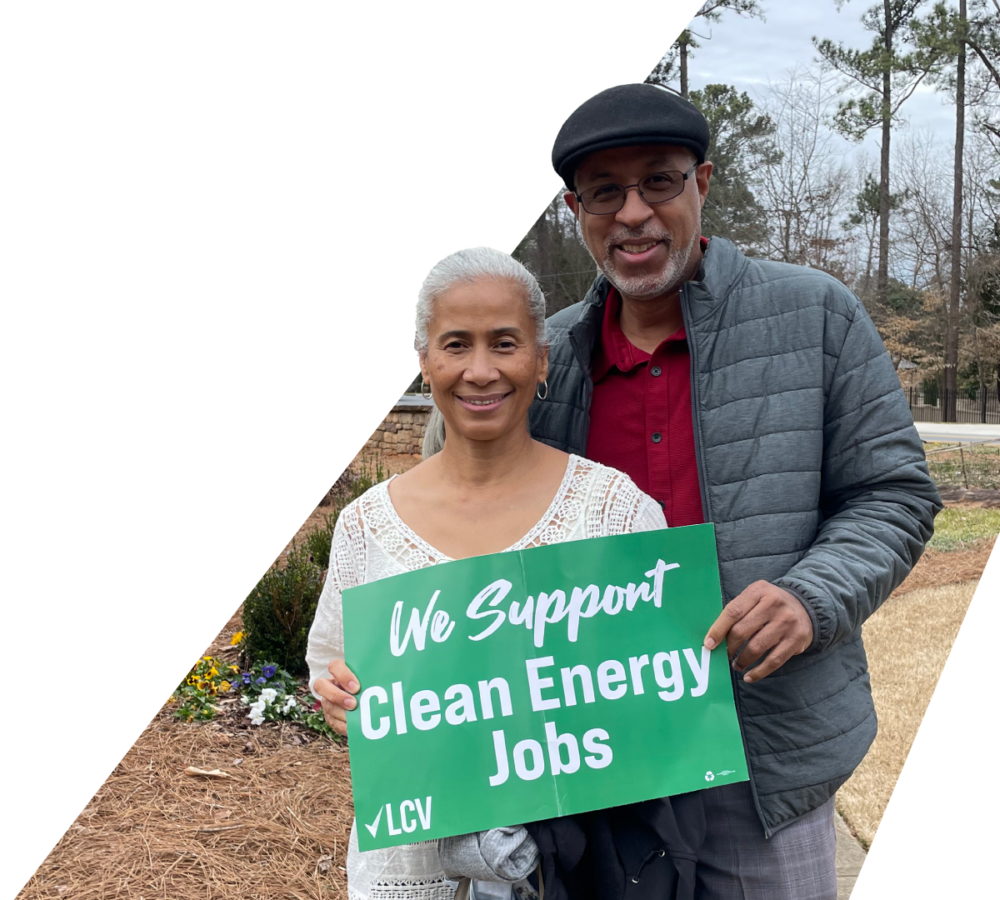A couple holding a green LCV sign that reads We Support Clean Energy Jobs
