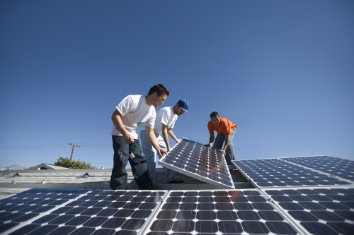 Three workers installing solar panels