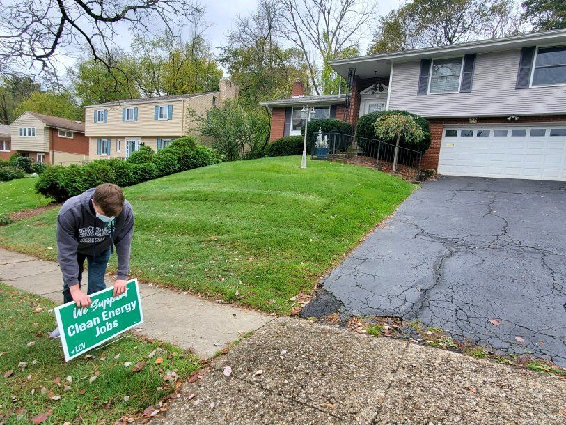 Volunteer placing a yard sign at a surburban home