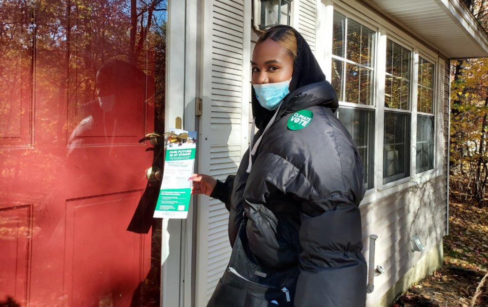 LCV Victory Fund Volunteer poses at a community member's front door as they leave marketing materials behind on the doorknob