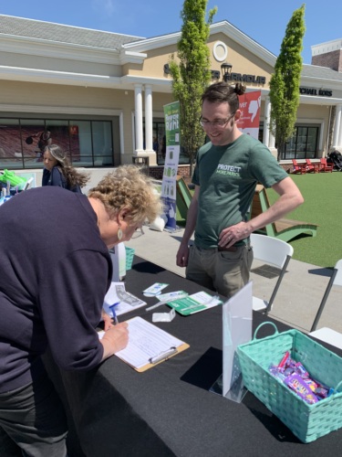 An LCV Volunteer watches as a member of the community fills out a volunteer sign up form