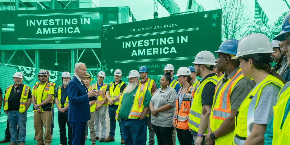 President Biden speaks with workers in high vis vests and hard hats at a semiconductor manufacturing facility in Durham, North Carolina on his Investing in America tour.