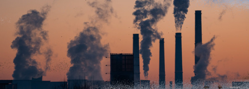 Smokestacks spewing pollution pictured at dusk.