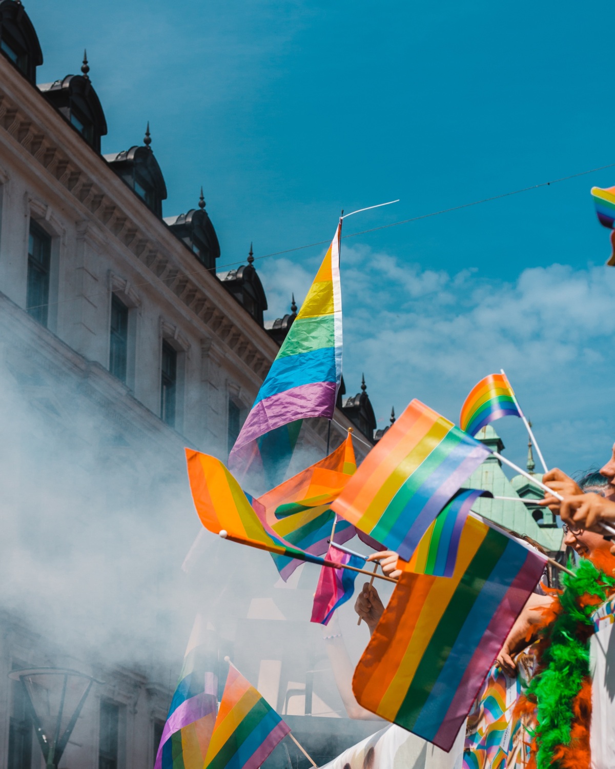 An image of people holding pride flags against a blue sky.