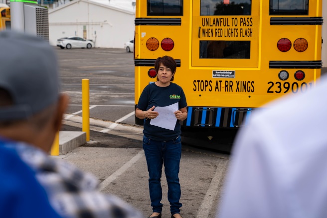 A Chispa Nevada activists speaks in front of an electric school bus.