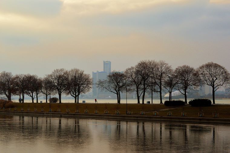 Park pathway extending into a lake, with fogged view of city in the background.