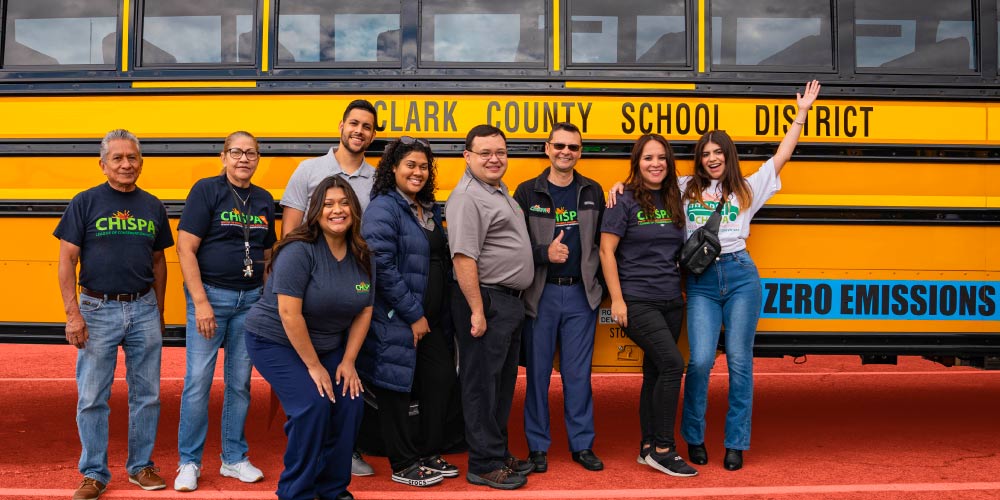 Chispa Nevada staff members pose in front of a zero-emissions electric school bus in Clark County.