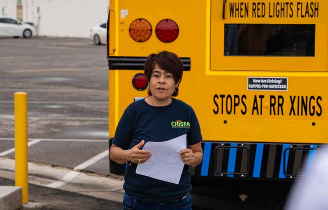 Chispa Nevada promotora Ivon Meneses speaks in front of a new electric school bus in Clark County.