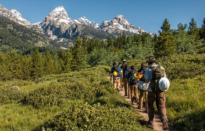 Climate corps volunteers hiking towards a mountain.
