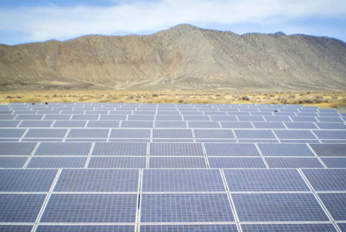 A field of solar panels in front of a mountain range in California.