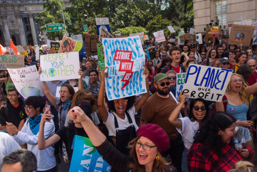 Large group of climate protestors marching and holding signs in Brooklyn New York.