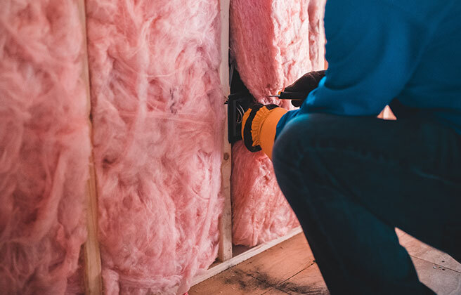 A worker installs home insulation.
