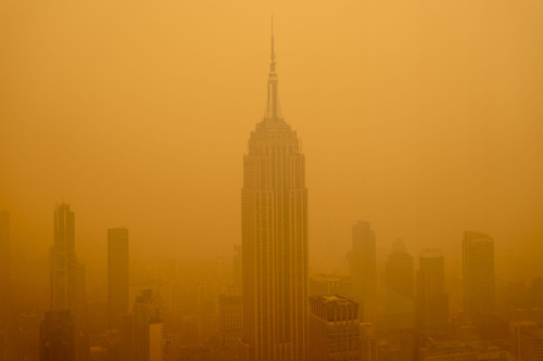 The New York City skyline obscured by thick, orange haze.