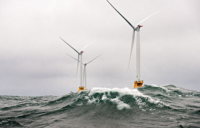 Offshore wind turbines in the middle of a storm with waves.
