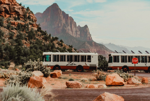 Two shuttles drive through Zion National Park.
