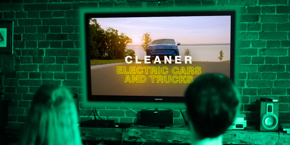 Two people sit watching a Clean Energy ad on TV 