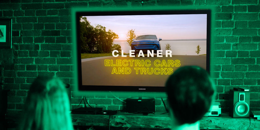 Two people sit watching a Clean Energy ad on TV 