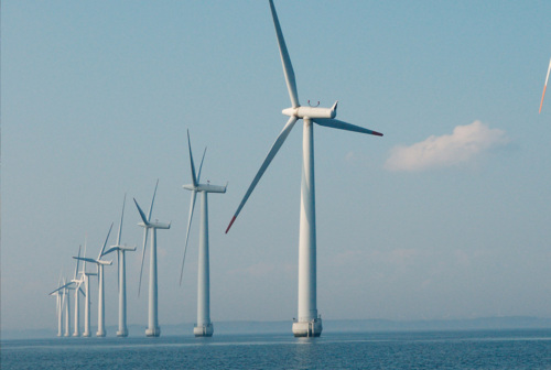Offshore wind turbines lined up in the ocean.