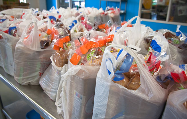 A large group of plastic grocery bags filled with food.