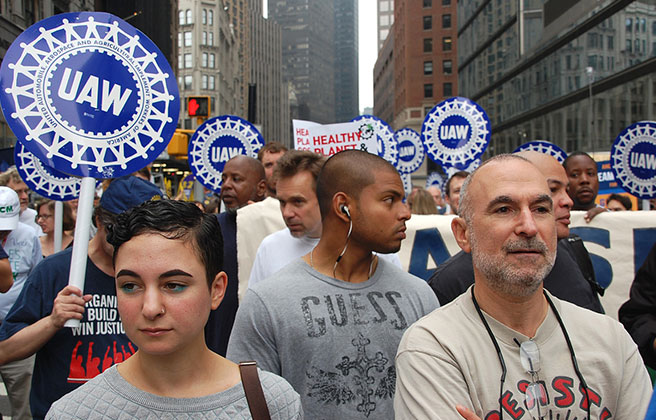 A group of protestors holding signs featuring UAW.