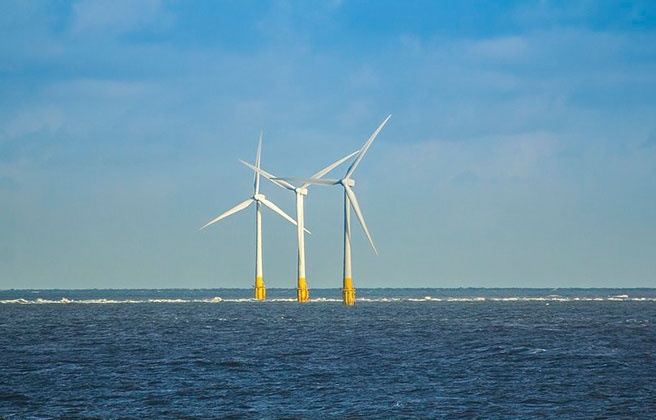 Wind turbines grouped close together offshore of the ocean.