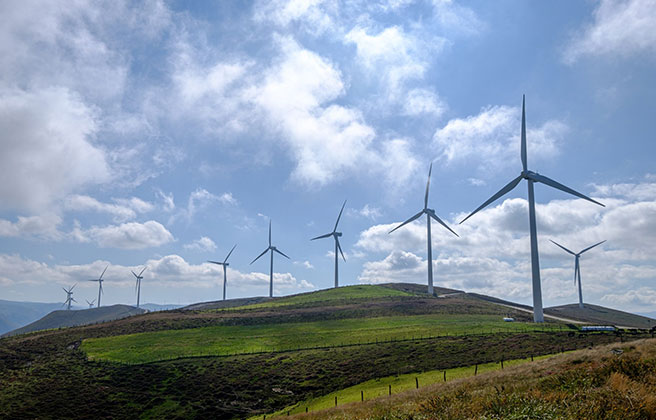 A series of windmills lined up on the horizon.