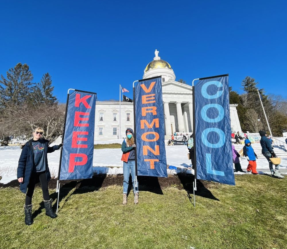 Activists posing with large flags reading "Keep Vermont Cool"