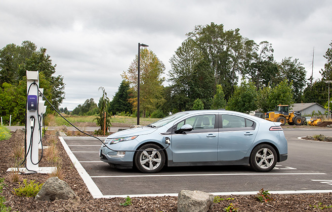 An electric vehicle is parked with an electric charger plugged into it.