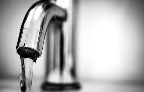 Closeup of a faucet with water pouring.