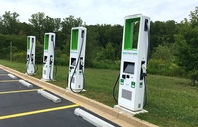 Four electric vehicle charging stations in a parking lot.