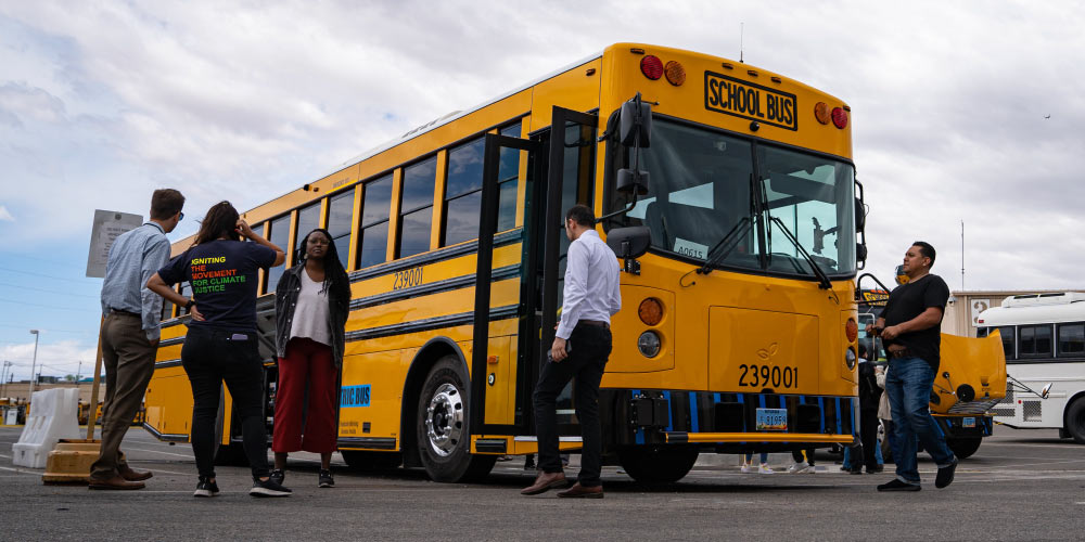 People gather around a new zero-emission electric school bus