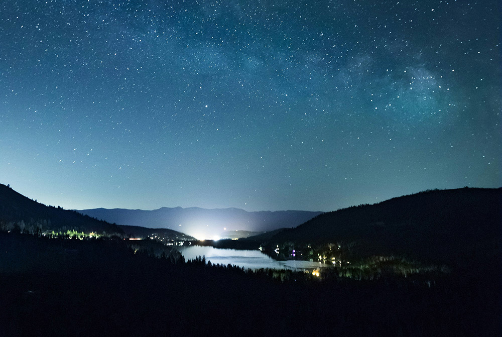 View of small city nestled in the mountains underneath a sky of stars.