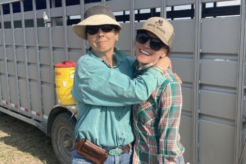 Maggie hugs her mom Ann in front of a cattle trailer.