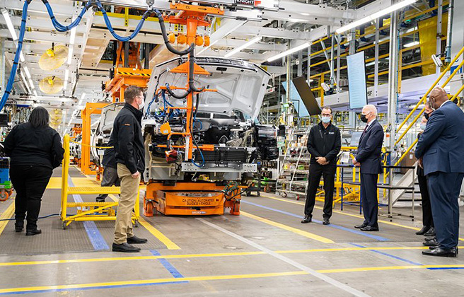 President Biden talking with EV car manufacturers in a factory.