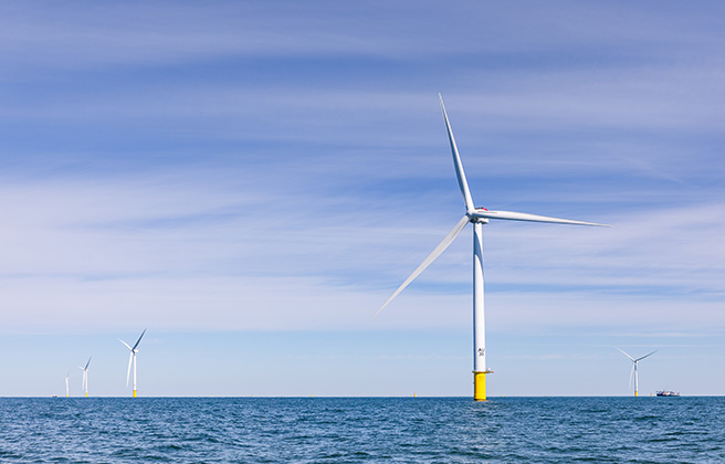 A row of offshore wind turbines in the ocean.