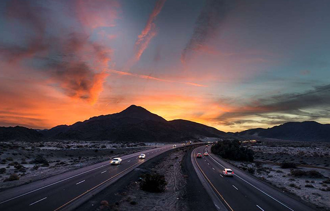 View of a U.S. Highway at sunset backdropped by a mountain range.