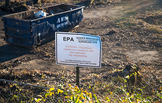 Quanta Resources Superfund Site with an EPA sign staked in ground and a large dumpster behind.