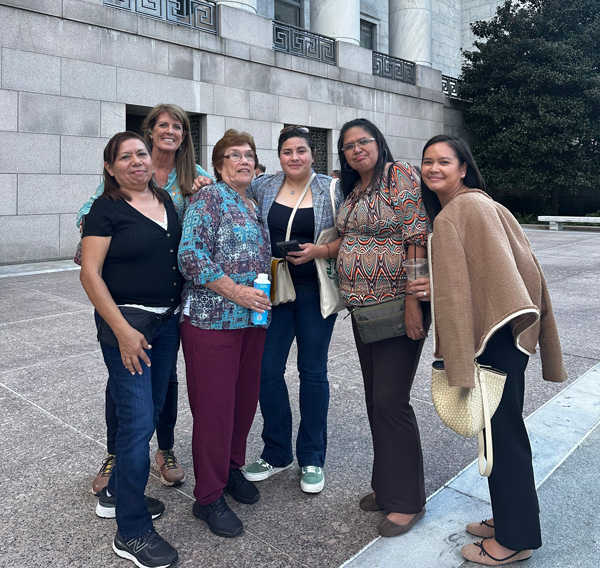 A group of six women stand outside the Rayburn House Office Building.