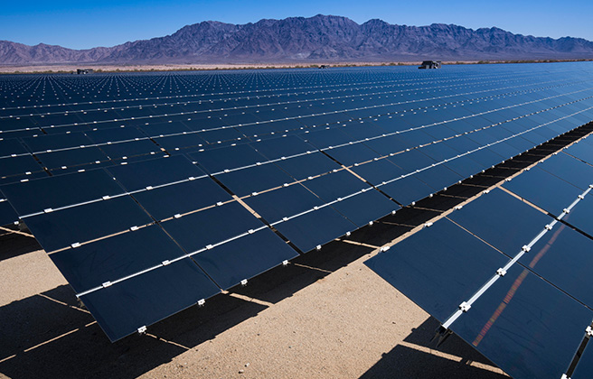 Large amount of solar panels set in front of a mountain in the California desert.