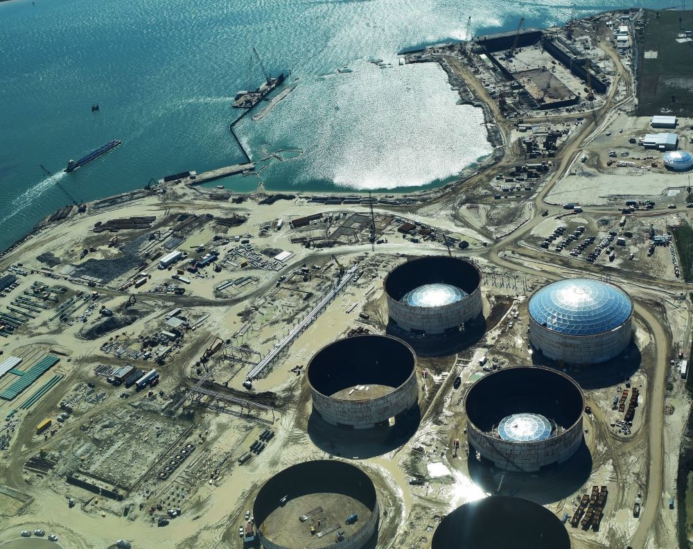 Overhead view of a huge industrial facility on the Gulf of Mexico shore, with two tanker ships in the harbor.