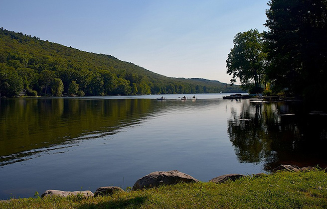 A body of water surrounded by trees and rocks at Kittatinny Lake in New Jersey.
