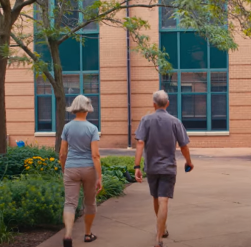 John and Carrie walking by some flowers