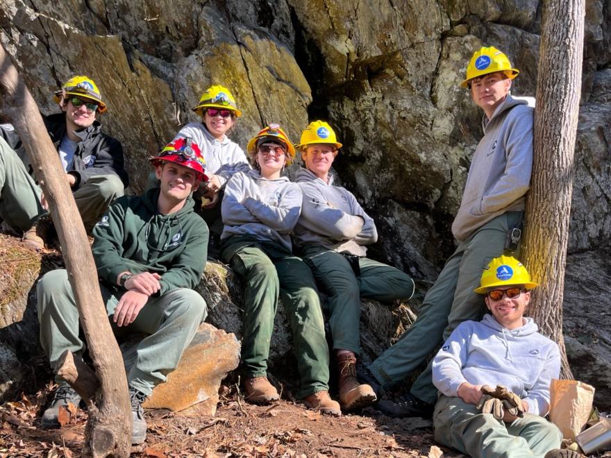 AmeriCorps Forest Corps members pose against the side of a mountain.