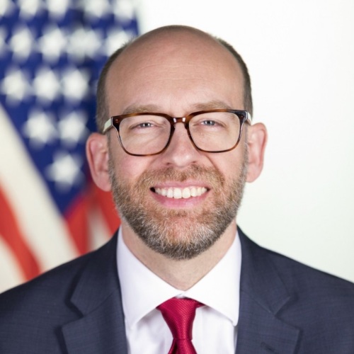 Russell Vought poses for a headshot in front of an American flag backdrop