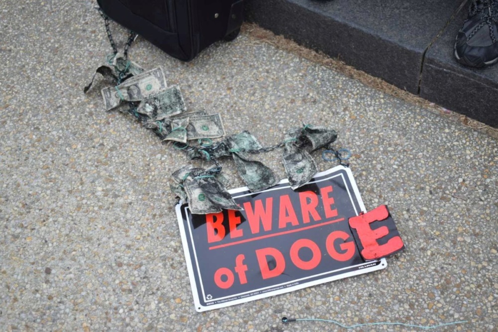 A "Beware of Dog" sign with an extra E taped to the end, so it reads "Beware of DOGE."