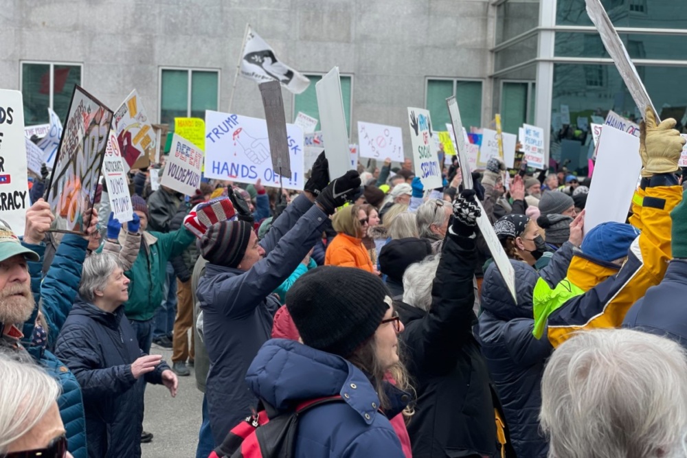 A crowd of protesters in Maine hold their signs high.