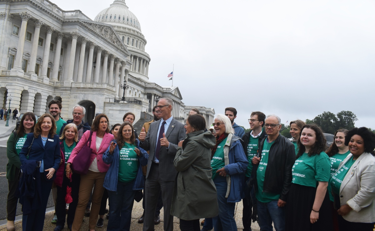 A group of people wearing green t-shirts stand outside the U.S. Capitol building.
